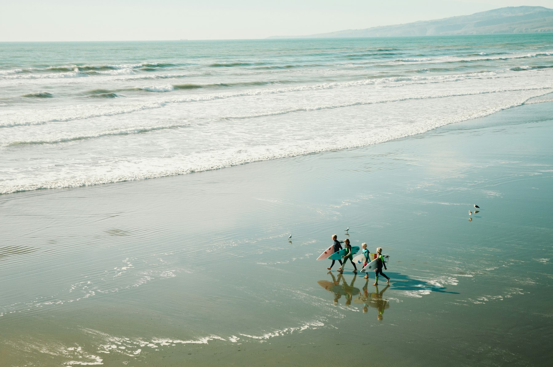 Surfers carrying boards along the beach